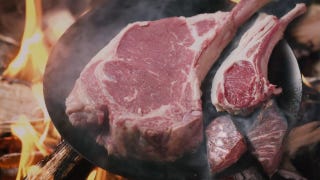 Three different types of meat, sizzling away on a large metal skillet.