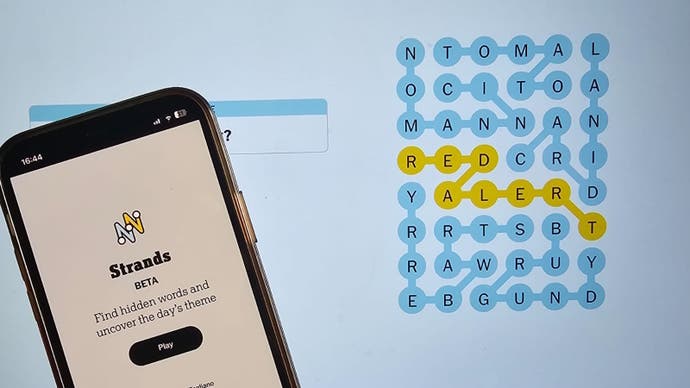 A solved Strands puzzle on a laptop screen with a phone displaying the NYT Strands login page in the foreground.